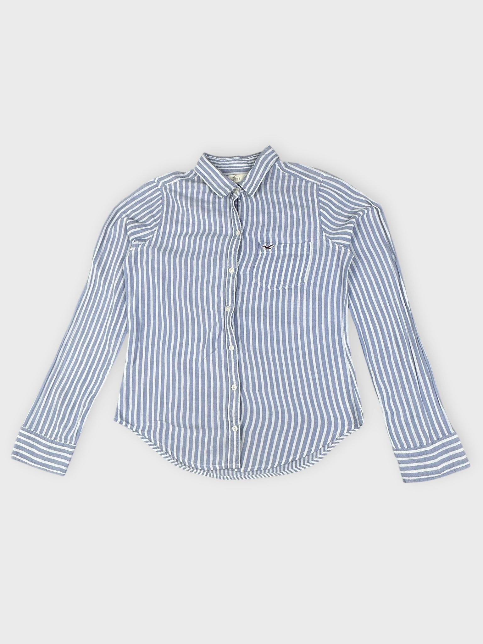 Front view of a blue and white striped button shirt featuring a small logo on the pocket.