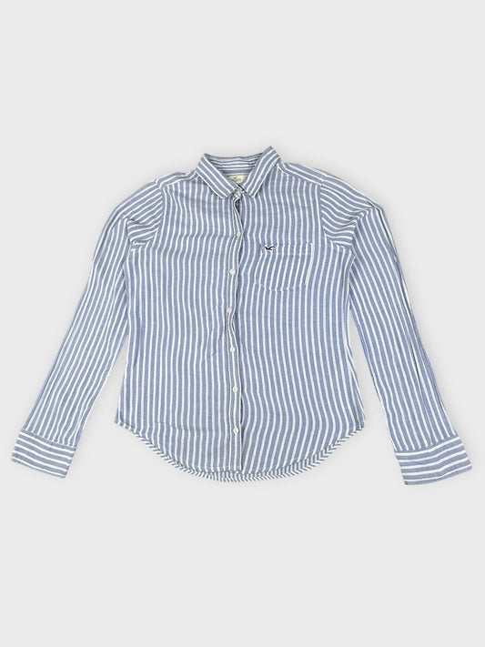 Front view of a blue and white striped button shirt featuring a small logo on the pocket.