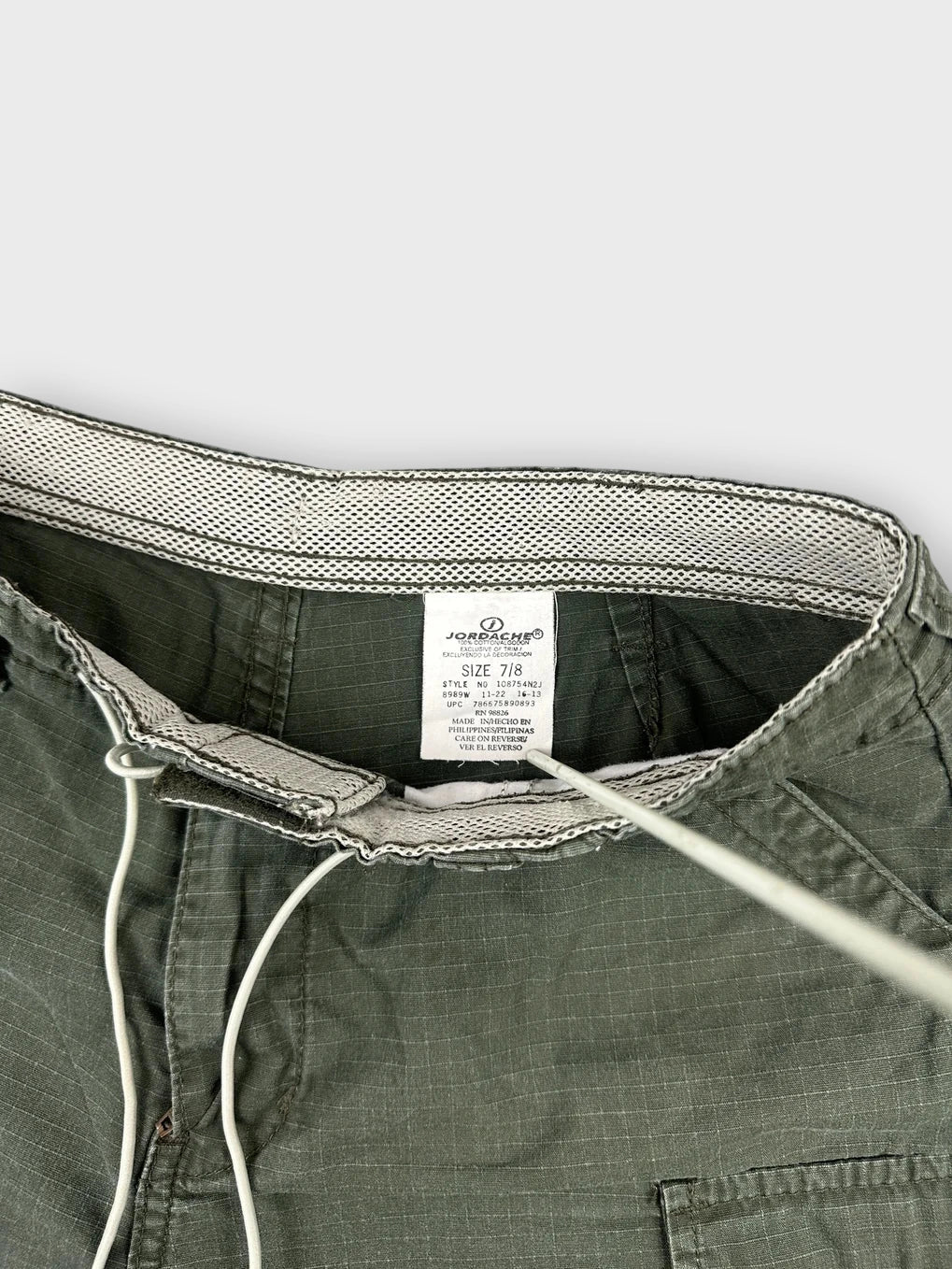 Detail view of olive cargo mini shorts with drawstring and mesh waistband.