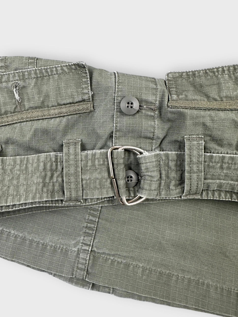Detail view of an olive mini skirt with pockets and a button closure.