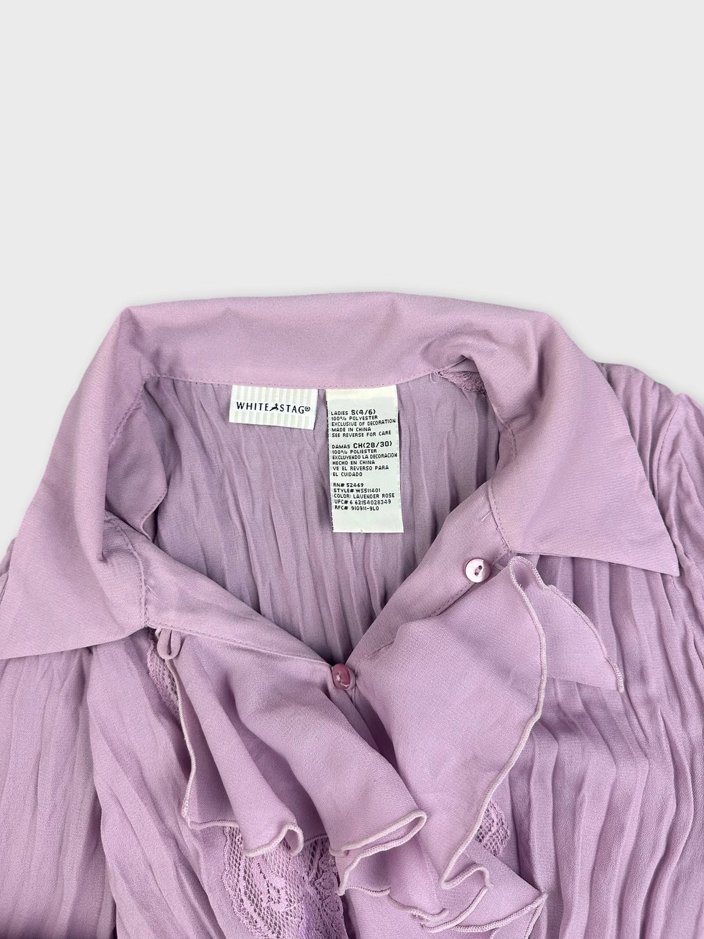 Detail view of a pink button-up shirt with ruffled trim and pleated texture.