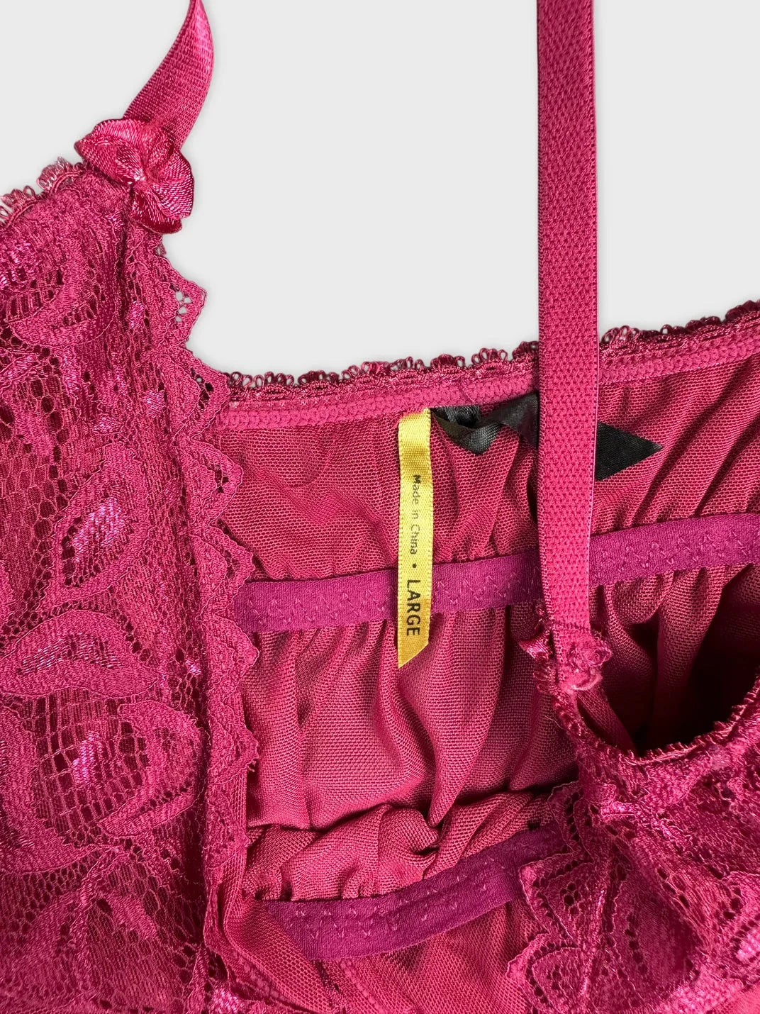 Back view of a pink lace cami featuring floral trim and spaghetti straps.