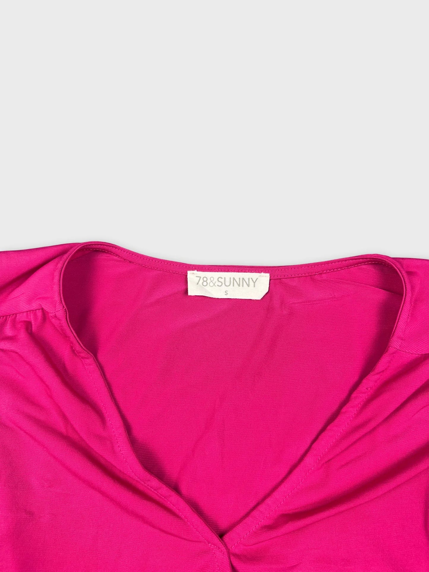 Detail view of a pink sleeveless top with a deep neckline.