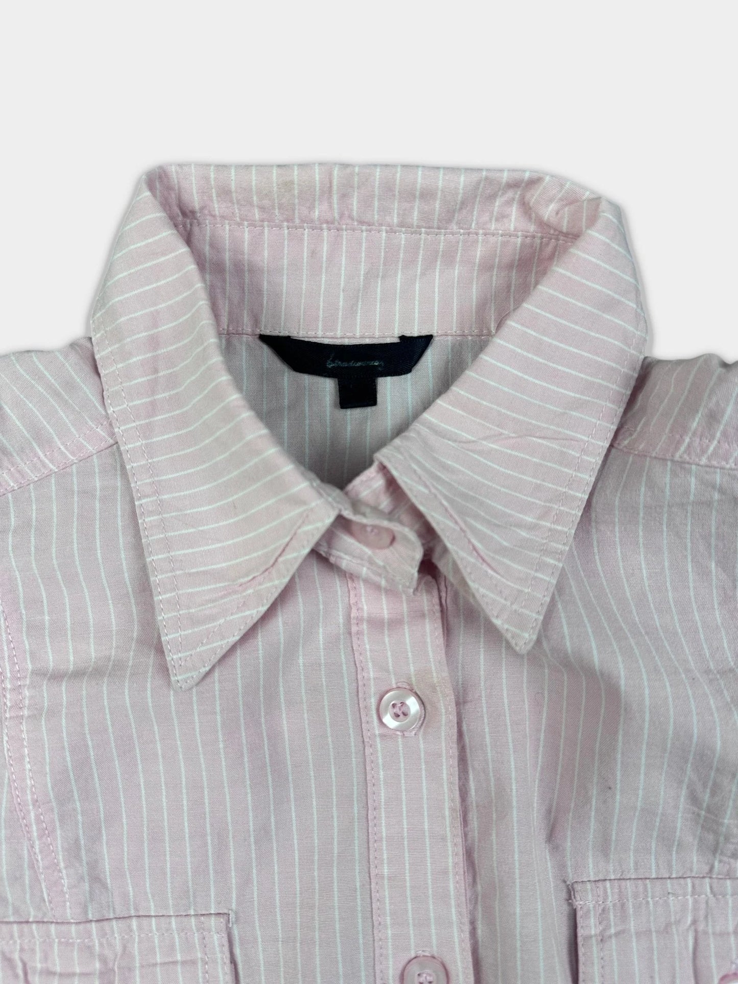 Detail view of a pink pinstripe short sleeve shirt with collar and buttons.