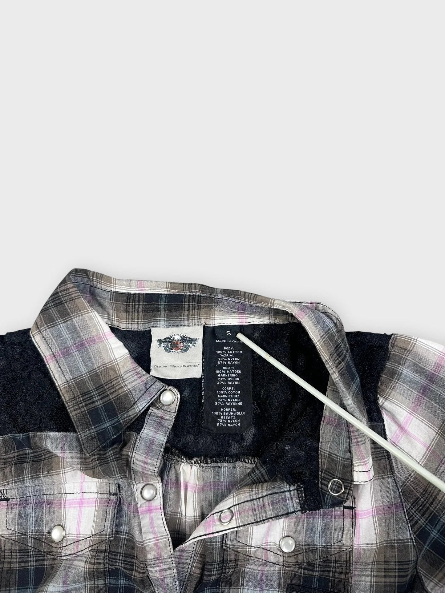 Detail view of a plaid button-up shirt in black and pink tones.