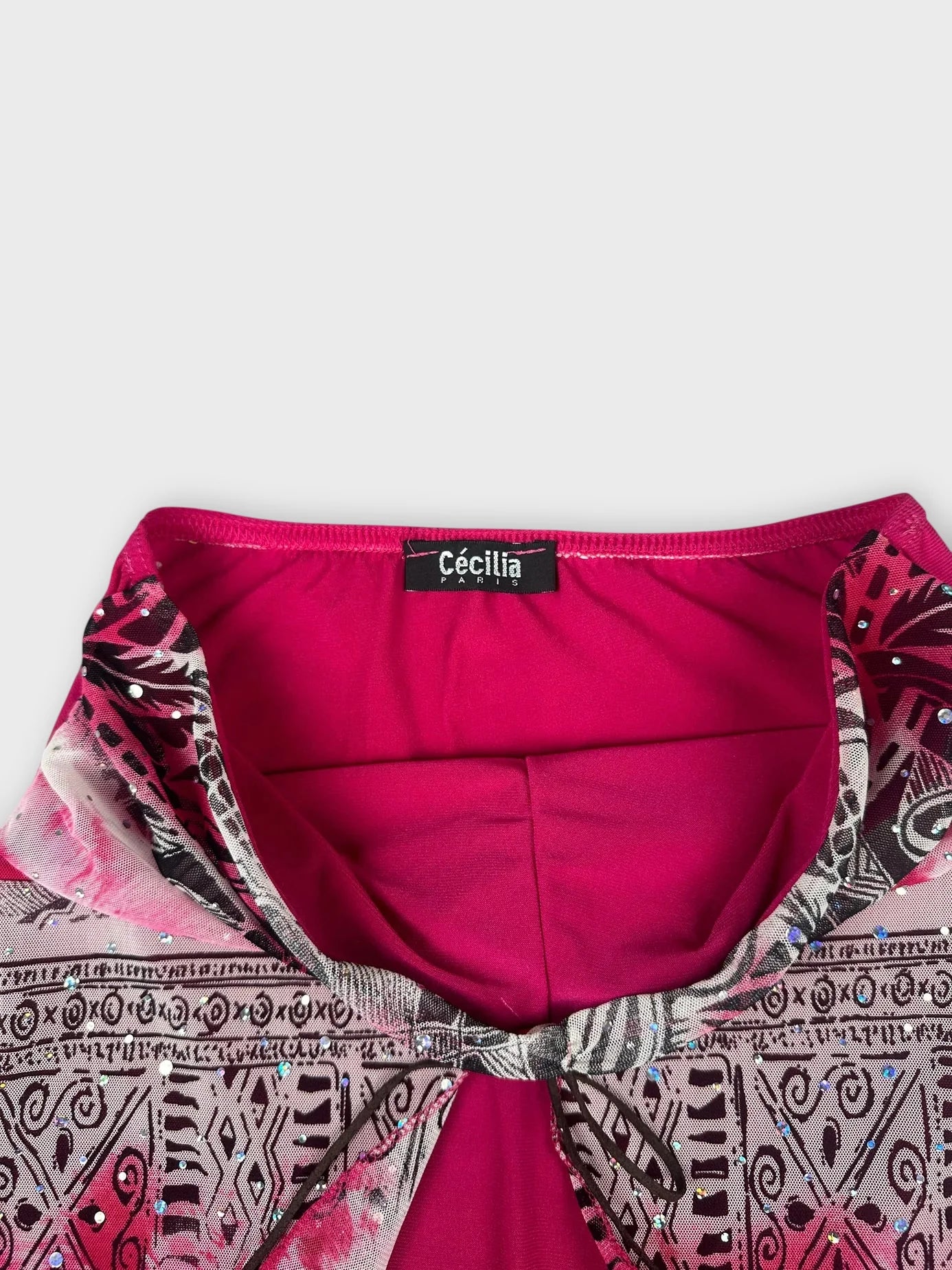 Detail view of a psychedelic strapless top in bright pink with abstract patterns.