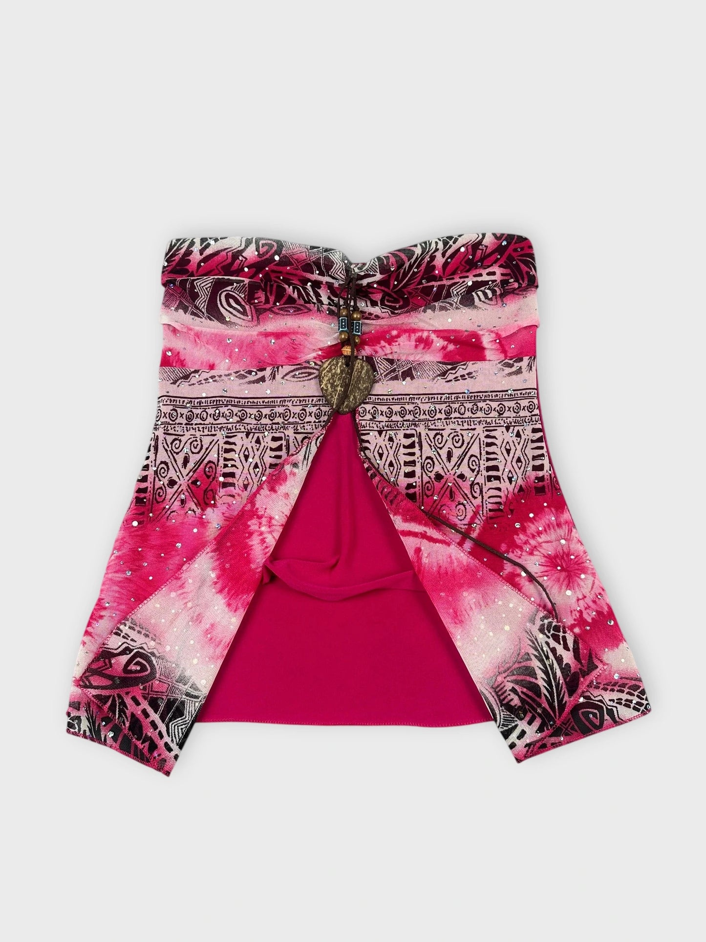 Detail view of a pink strapless top with a heart charm and intricate patterns.