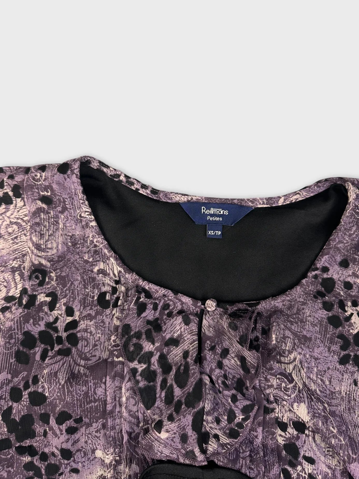 Detail view of a purple floral lace top with keyhole detail.