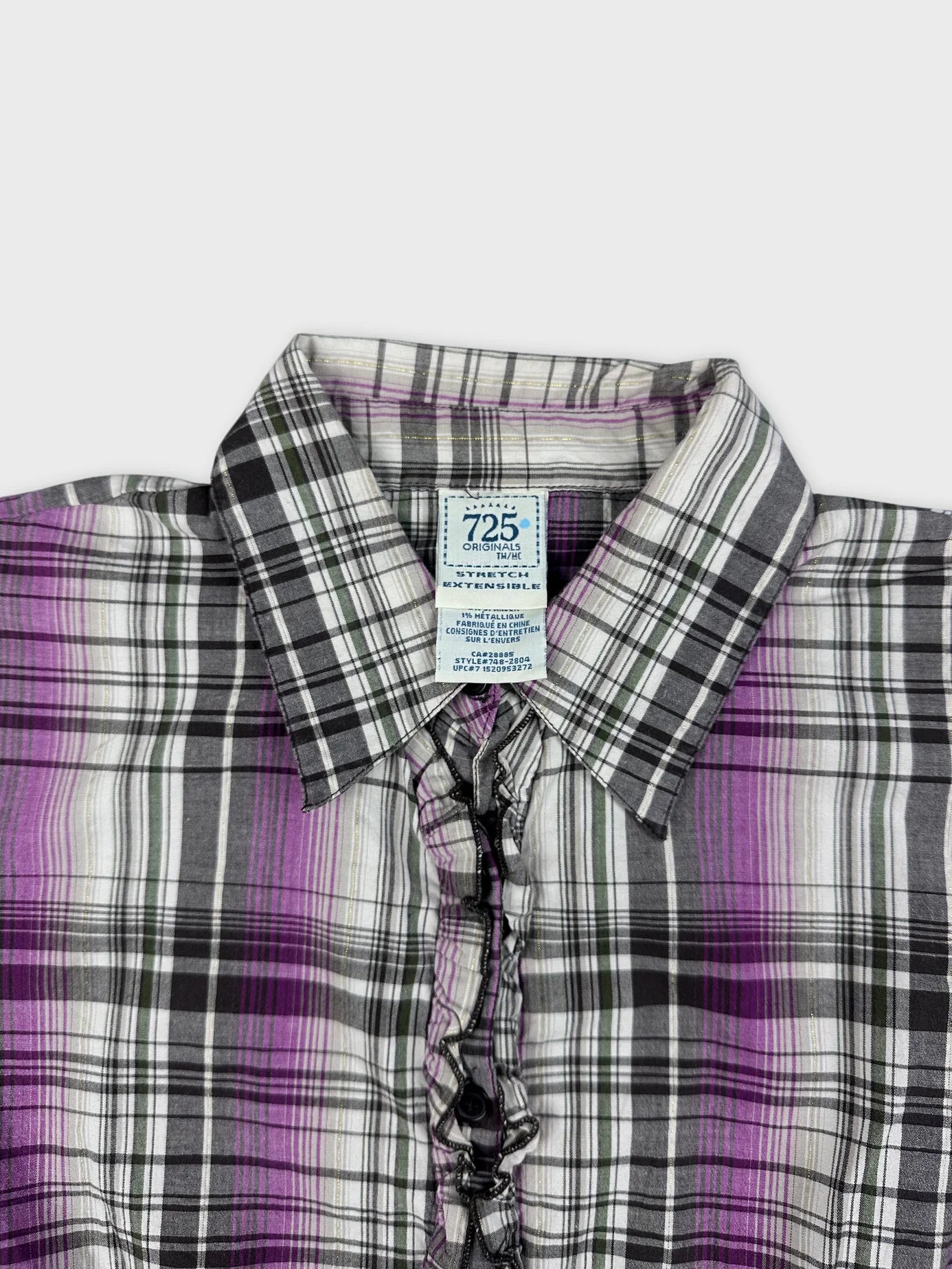 detail view of a purple plaid button-up peplum shirt showing ruffled trim