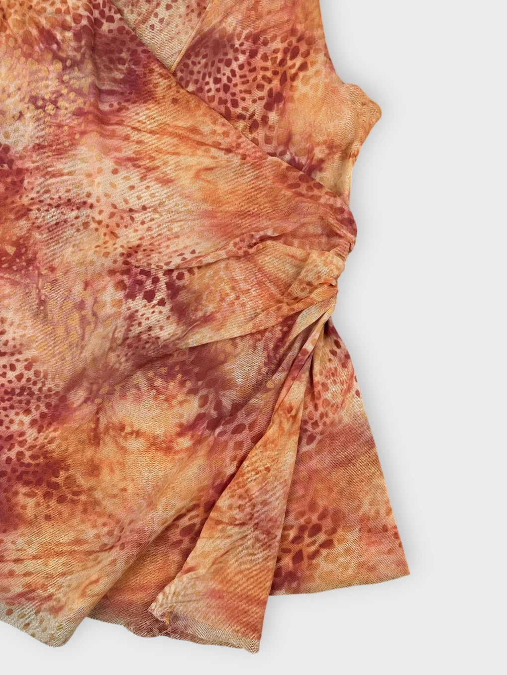 Detail view of rust tie-dye ruched top featuring soft orange tones.