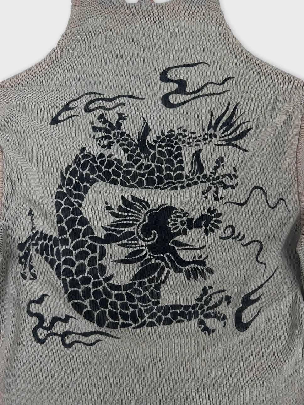 Detail view of a sheer long sleeve top featuring a black dragon print design.