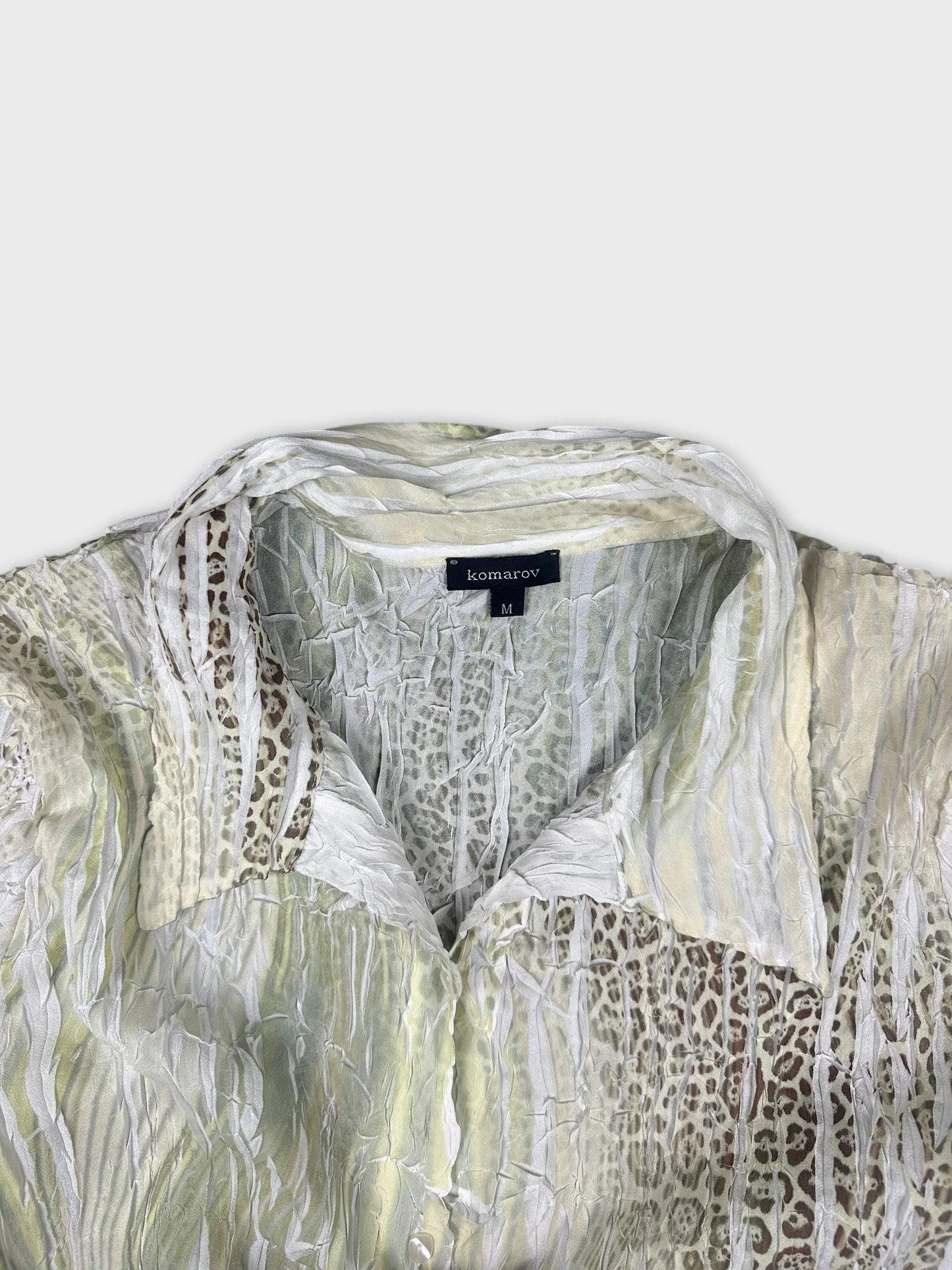 Detail view of sheer green button-up top with lace sleeves and textured pattern.