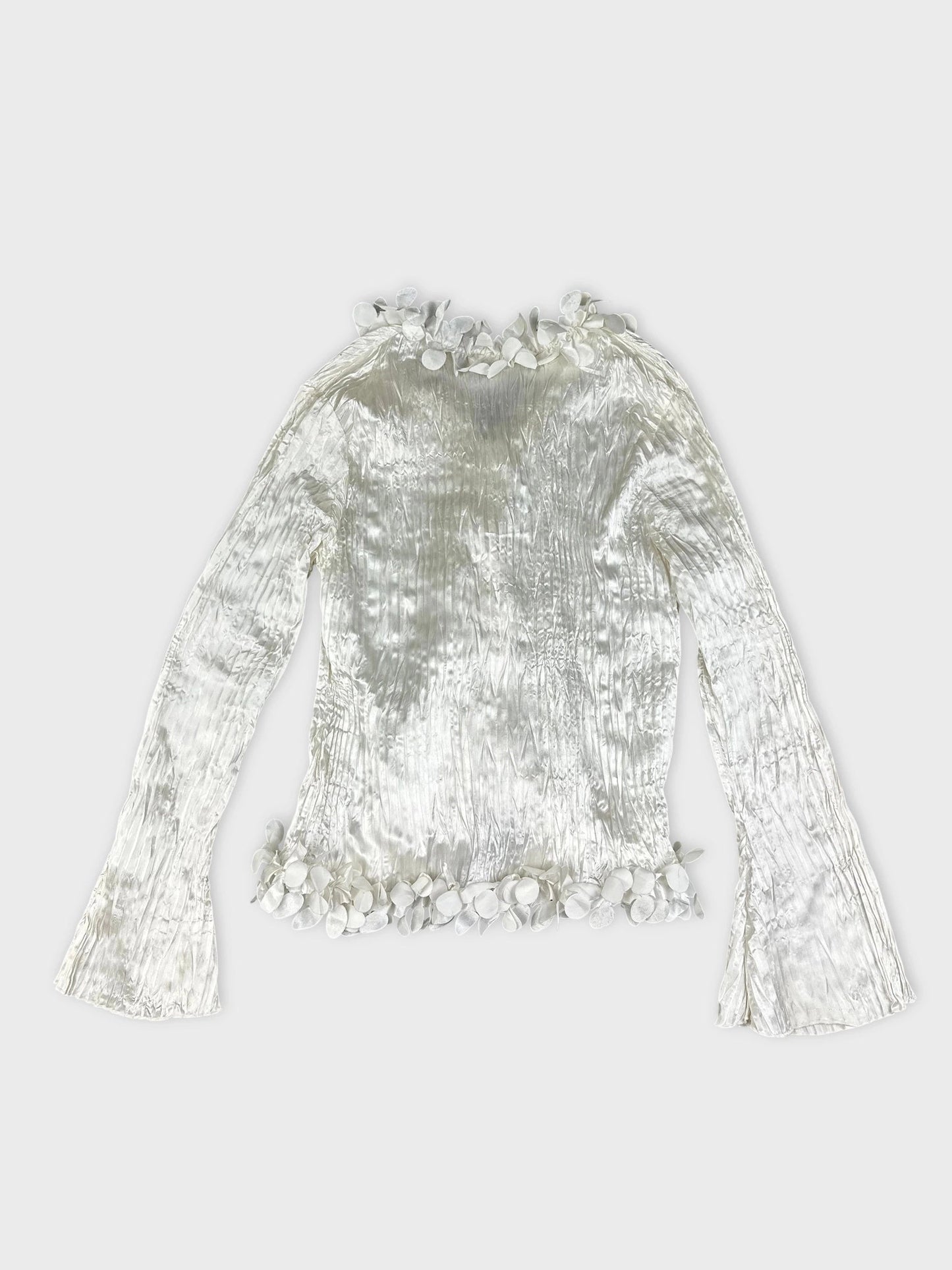 Back view of a shiny white long sleeve blouse with floral trim.