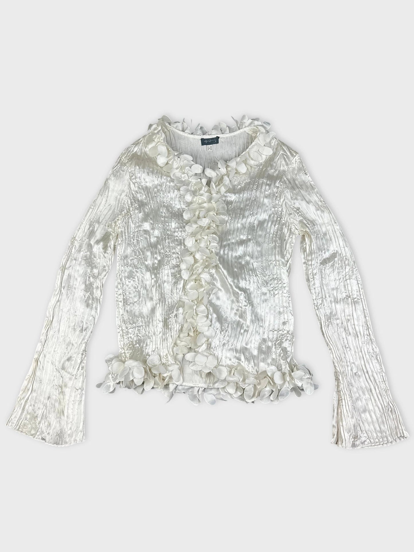 Front view of a shiny white long sleeve blouse with floral trim.