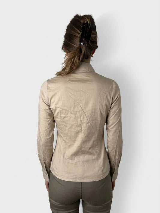 Back view of a beige button-up blouse with a ruched bust detail.