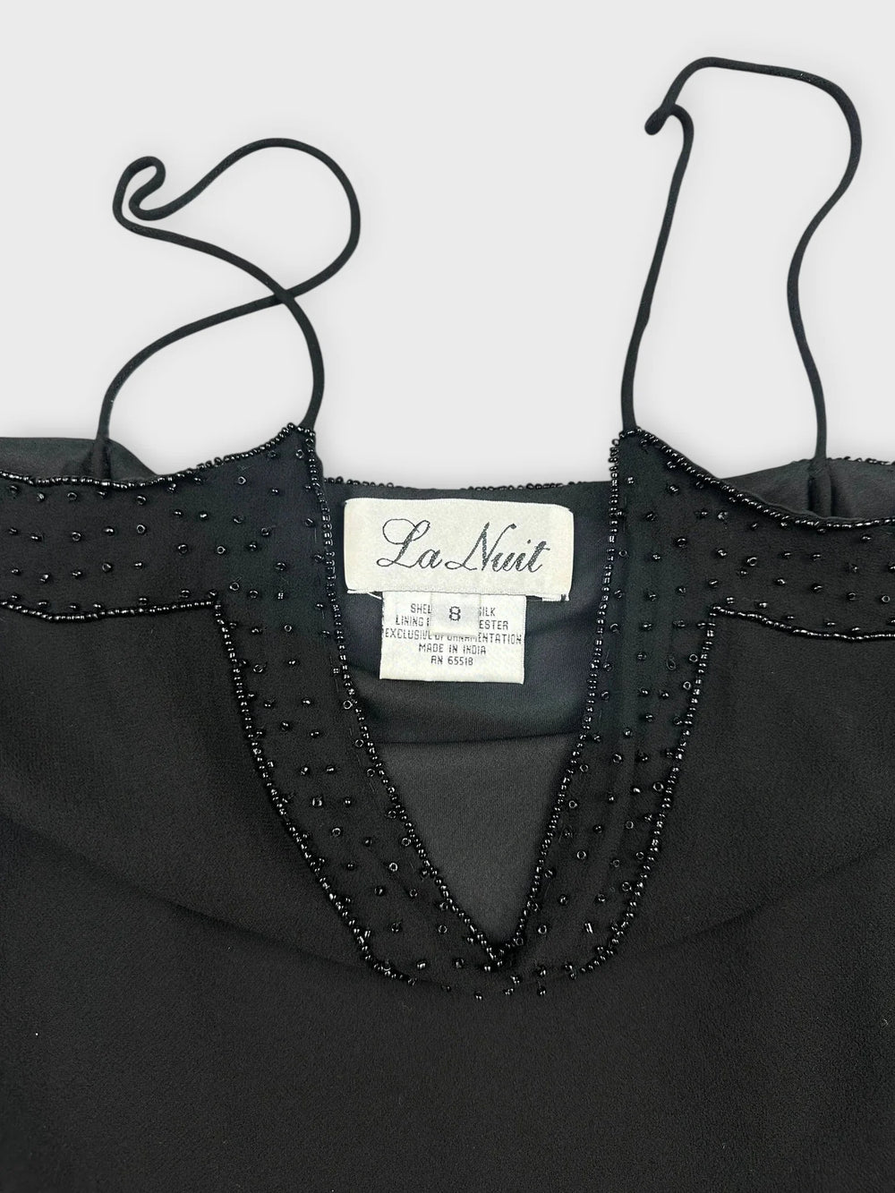 Front view of a black silk camisole featuring lace and bead detailing.