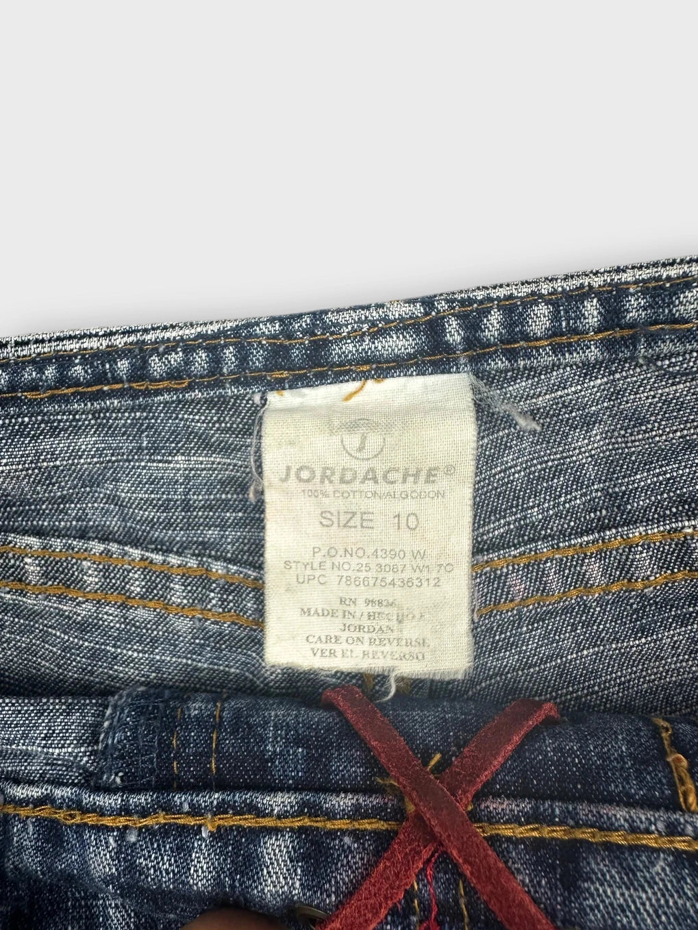Detail view of blue denim shorts showing frayed edges and contrasting stitch trim.