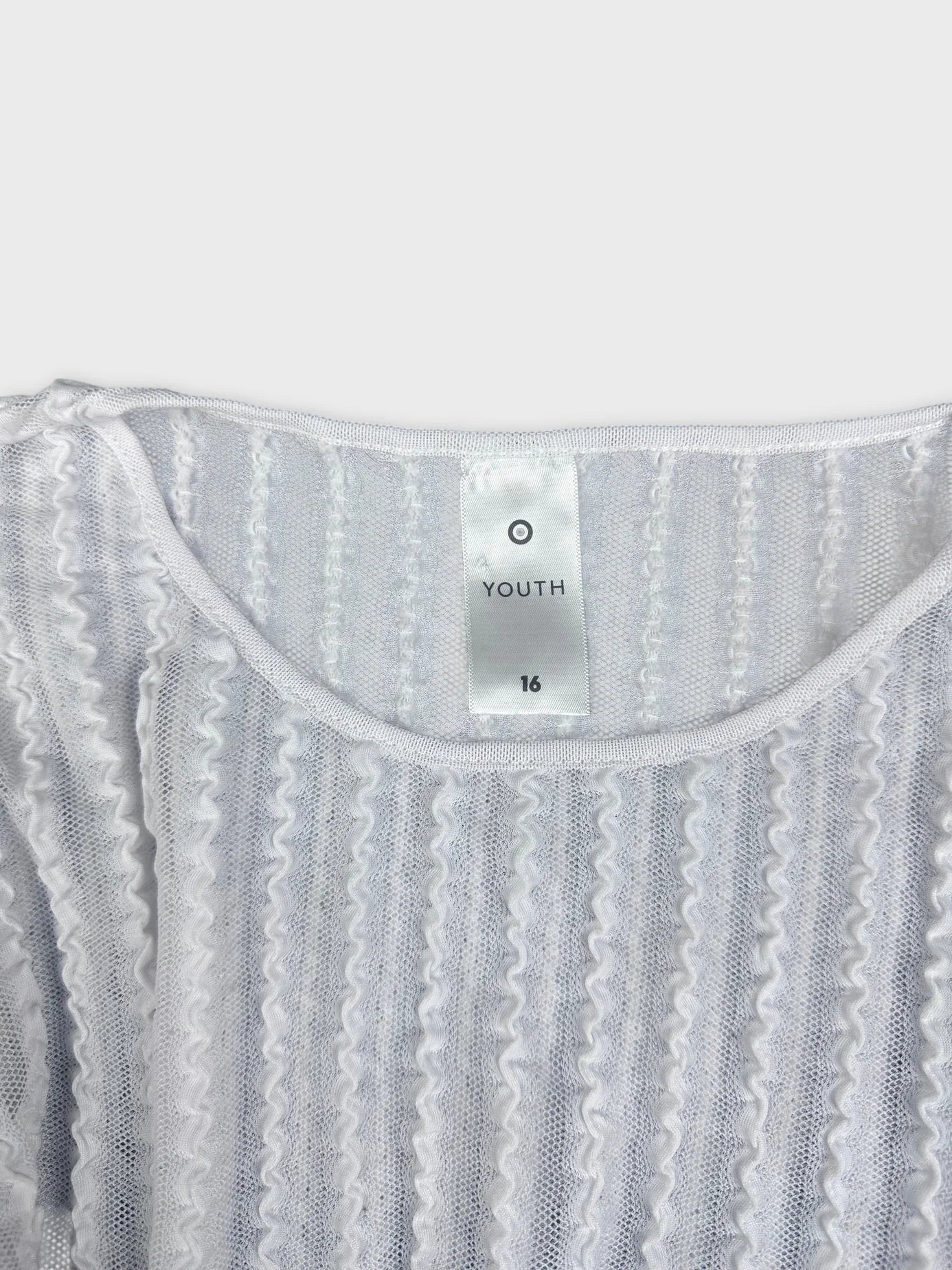 Detail view of white ribbed knit shirt with wavy texture.