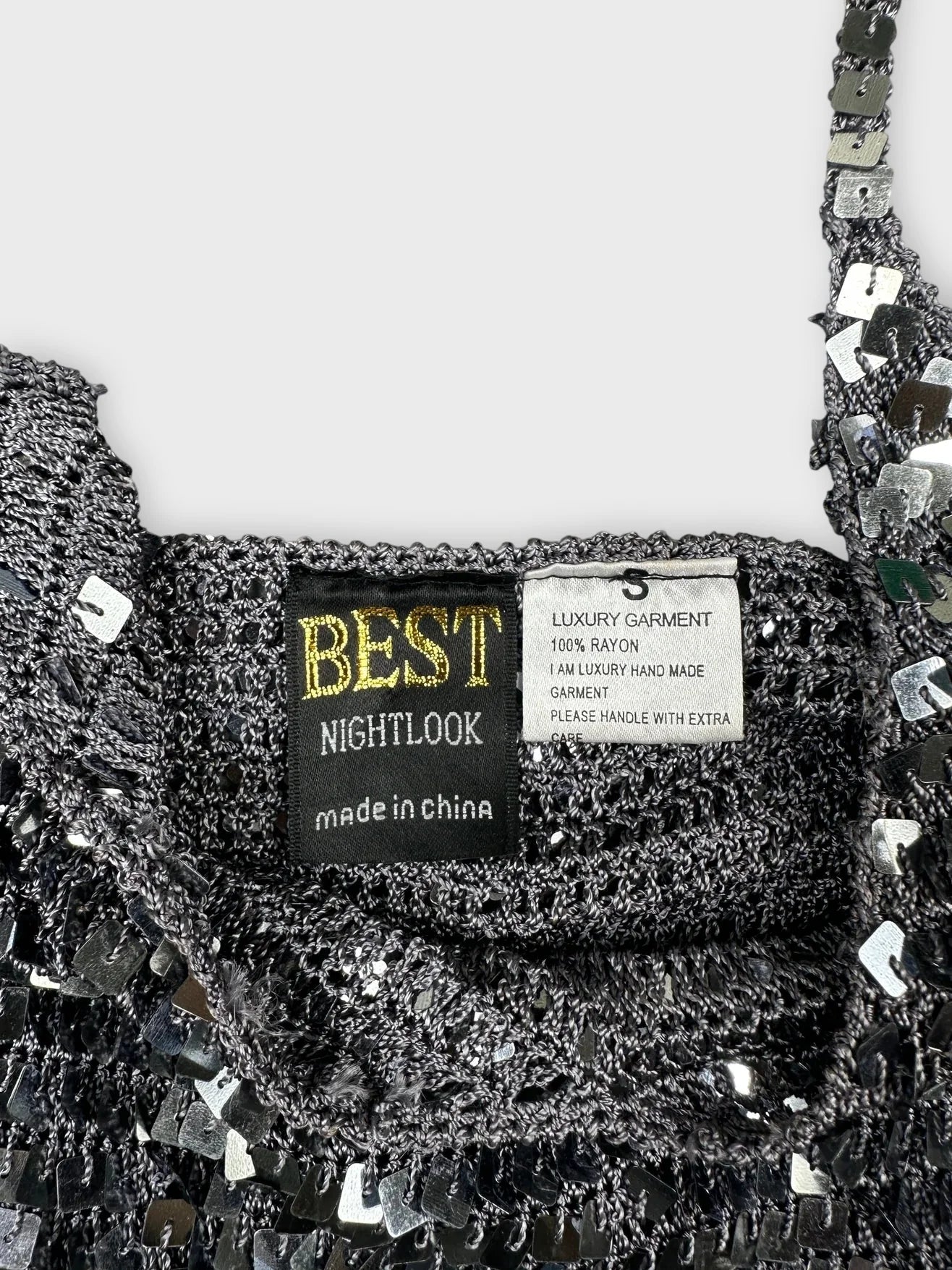 Detail view of a sparkly silver crop top with sequins and thin straps.