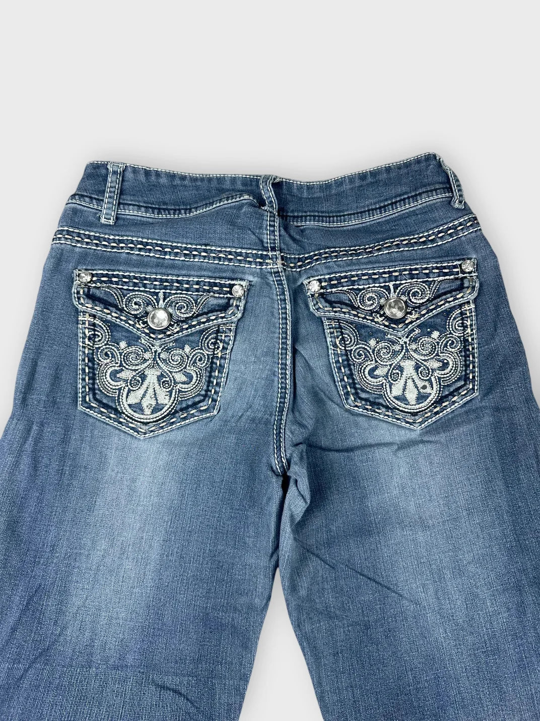Back view of stylish denim jeans featuring intricate embroidered pockets.