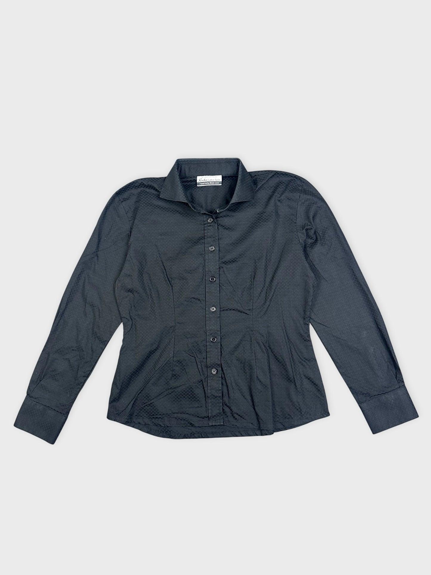 Detail view of a black shirt featuring a textured pattern and button-up front.