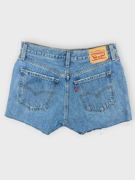 Back view of light blue denim mini shorts with frayed hem.