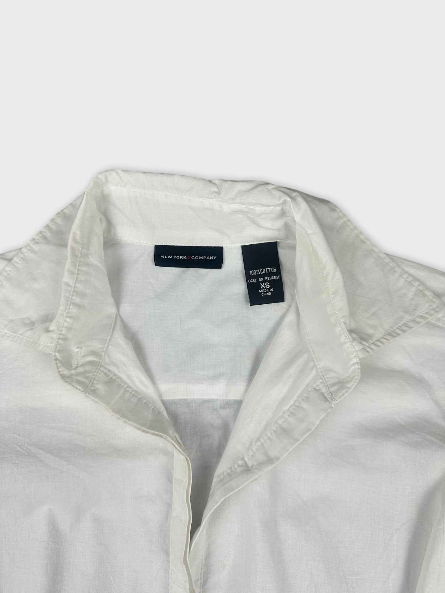 Detail view of a white cotton peplum button-up shirt collar and placket.