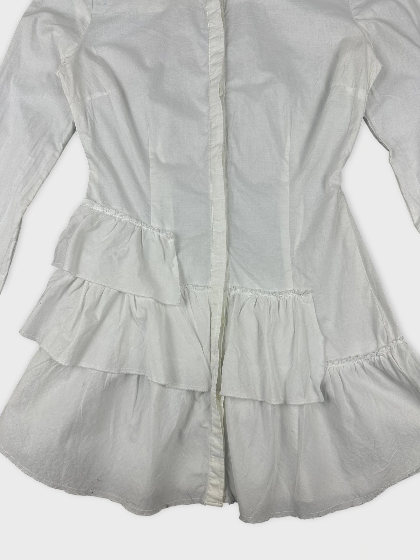 Detail view of a white cotton peplum button-up shirt with layered ruffle trim.