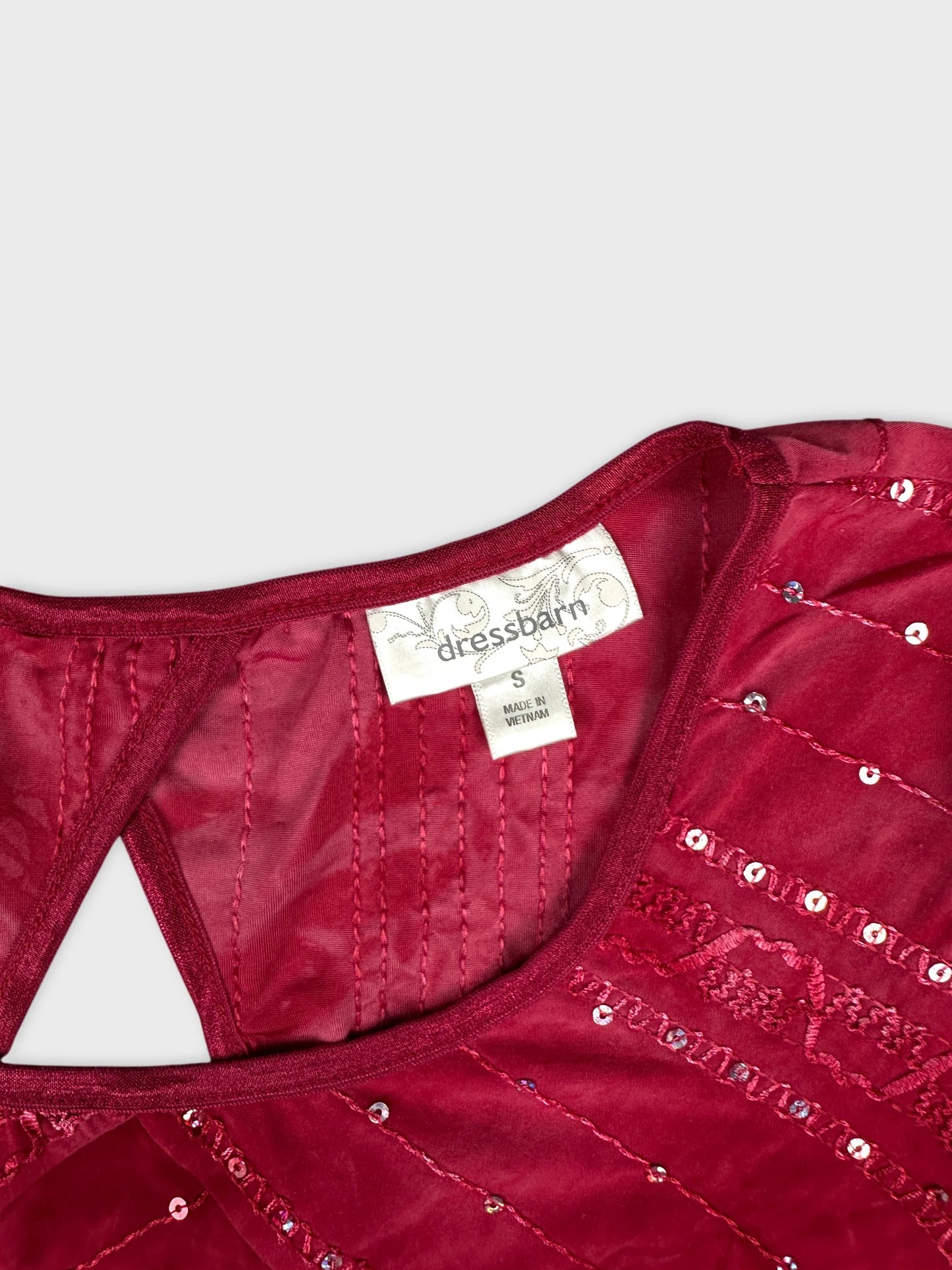 Detail view of burgundy body shirt with sequined pattern and textured stitching.