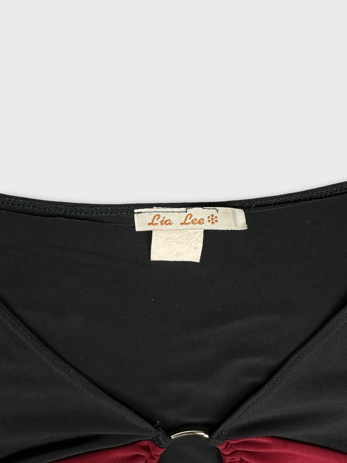 detail view of a black body shirt with red trim and a ring detail