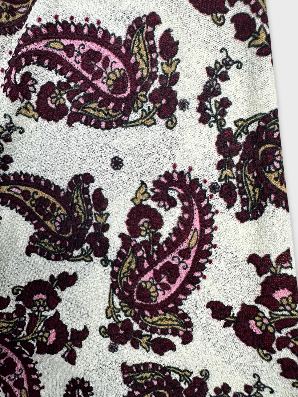 detail view of a body shirt featuring a burgundy paisley pattern on a light background.