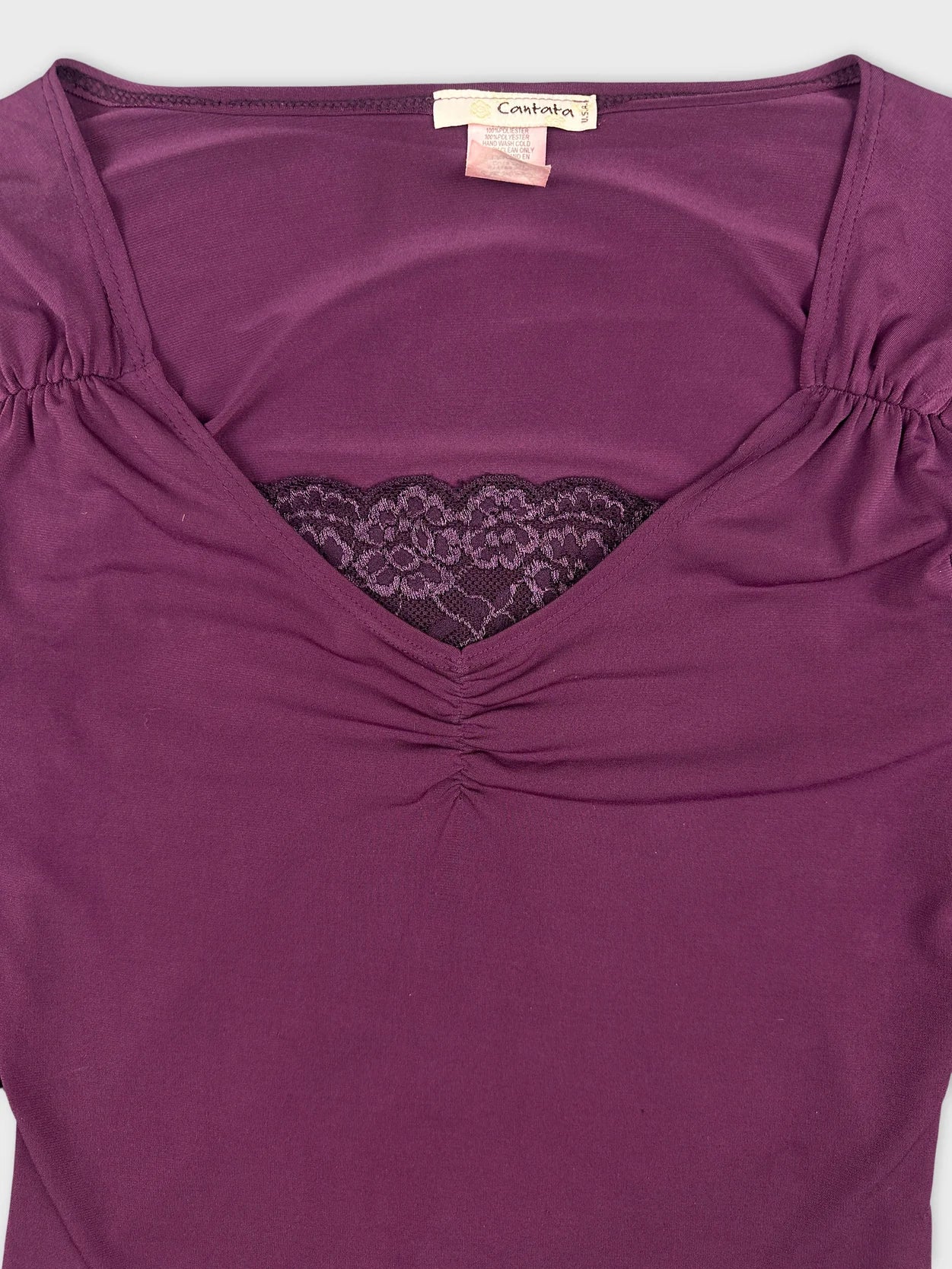 Detail view of a purple body shirt featuring lace trim at the neckline.