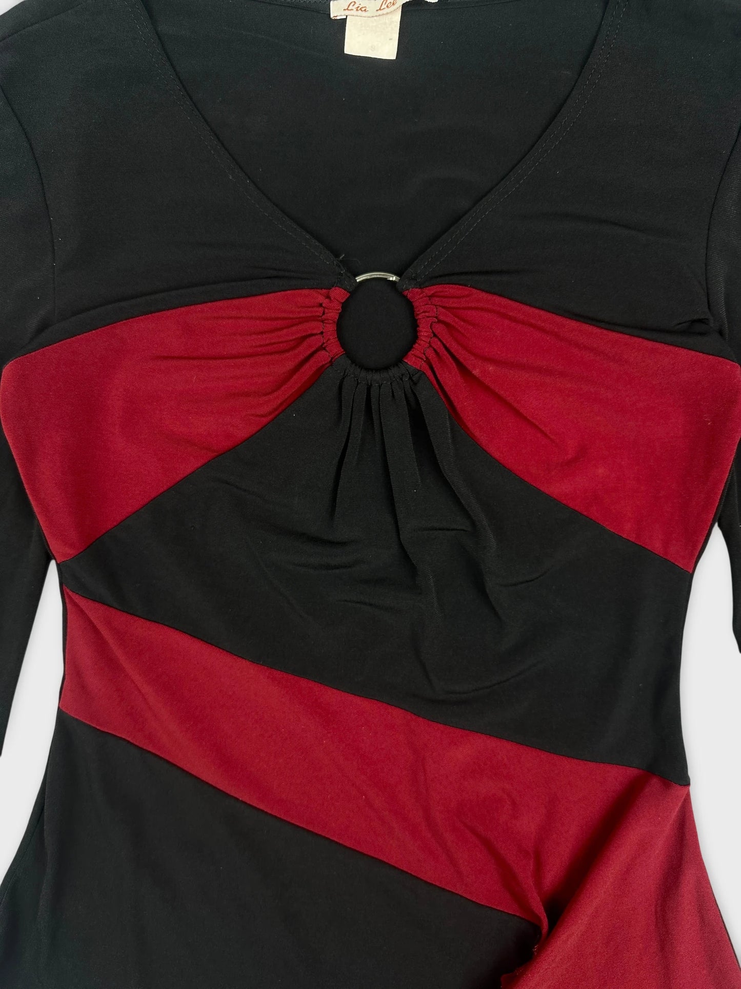 Detail view of a black and red women's body shirt with a ring detail.