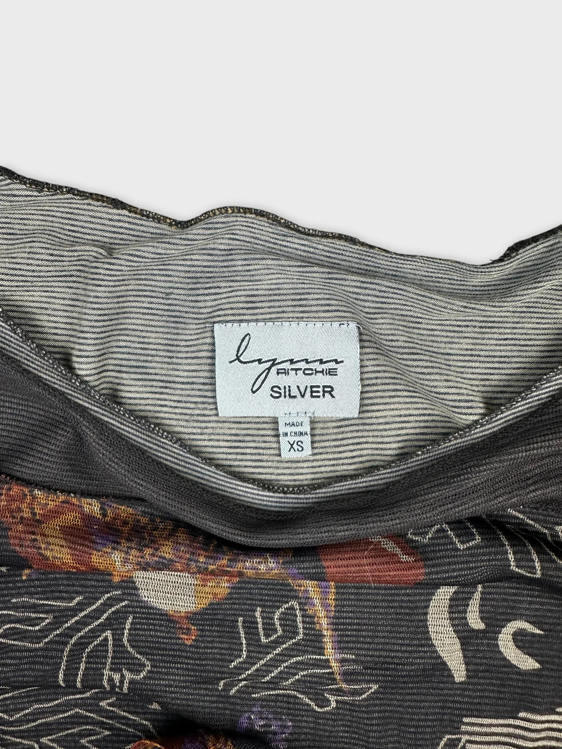 Detail view of a women's body shirt in gray with colorful floral print
