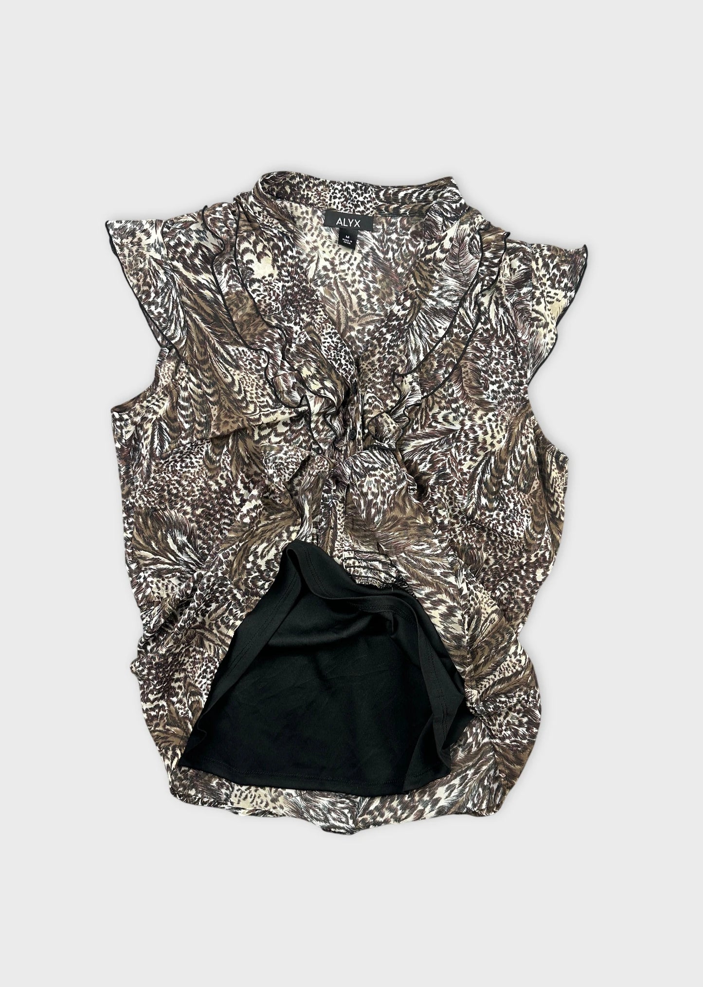Detail view of a brown patterned women body shirt with ruffled neckline.