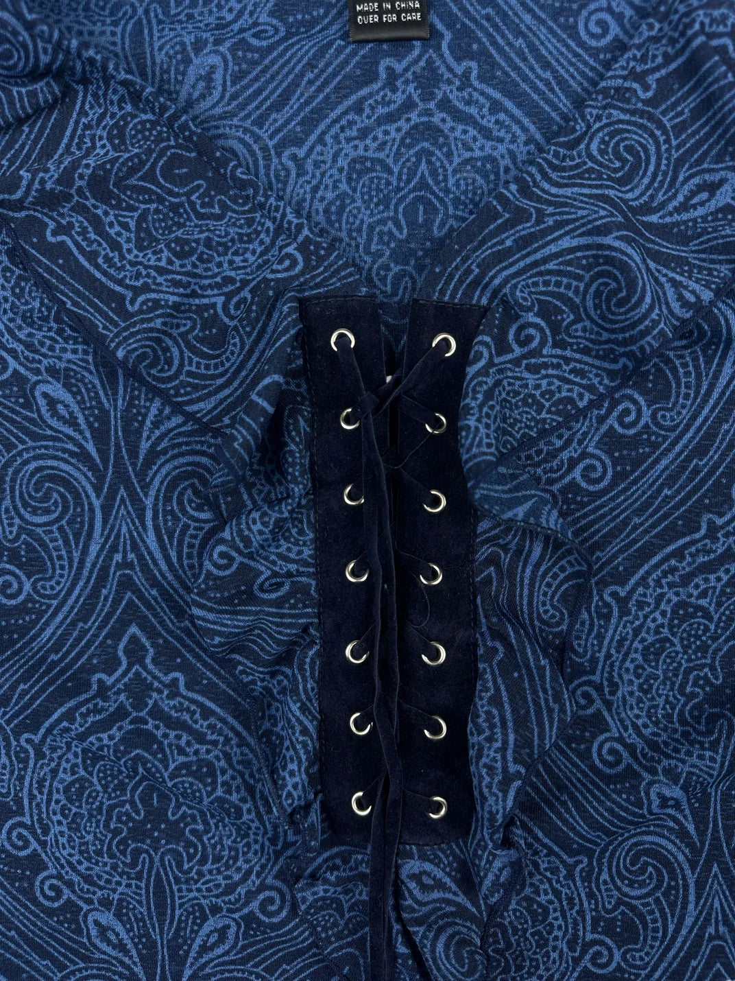 Detail view of a navy body shirt featuring lace-up front detail and intricate pattern.