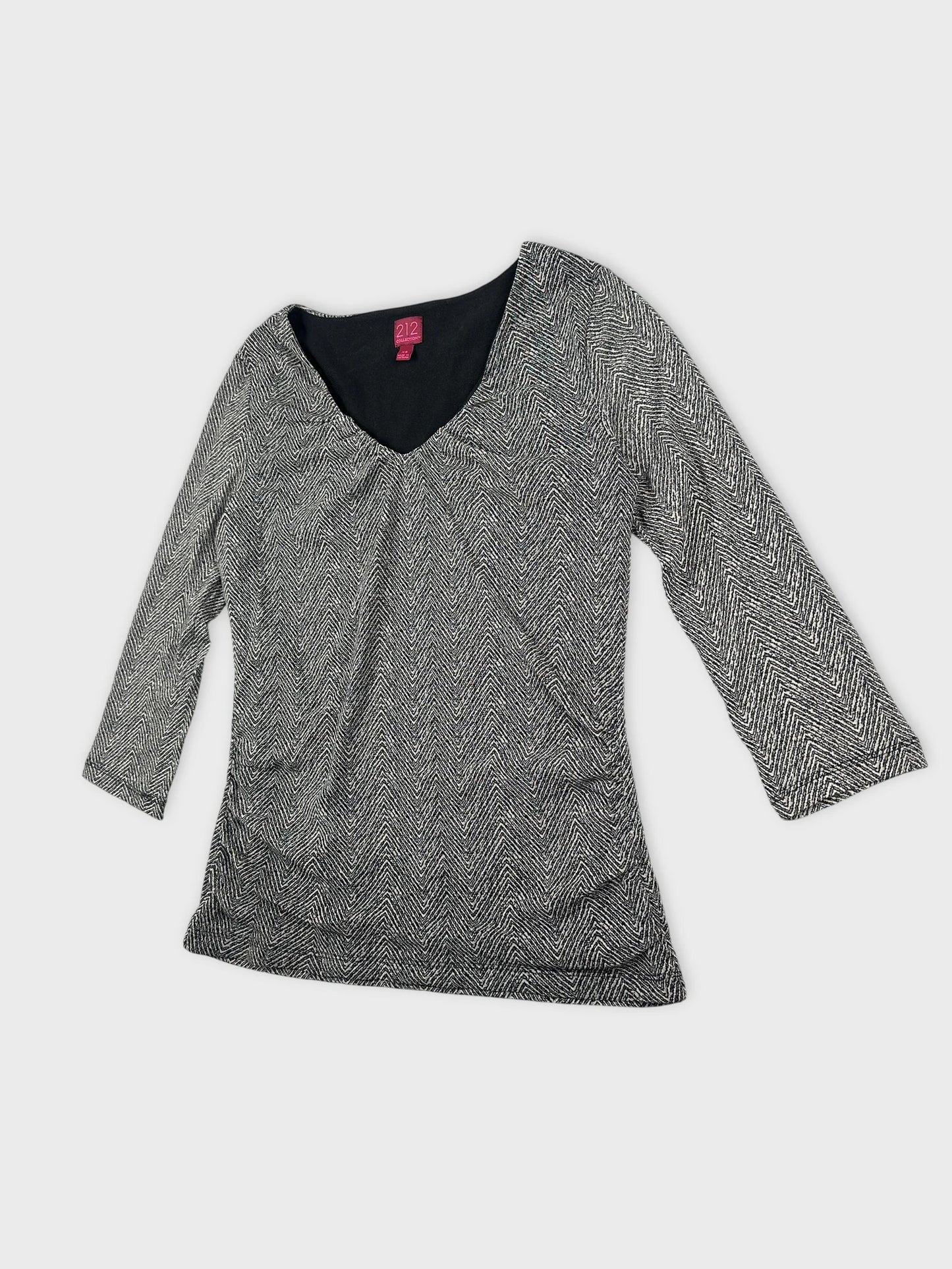 Detail view of a black and white herringbone body shirt with a v-neck.