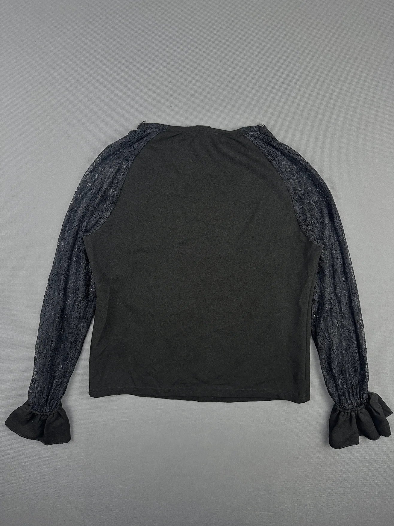 Back view of a black body shirt with lace sleeves and flared cuffs.
