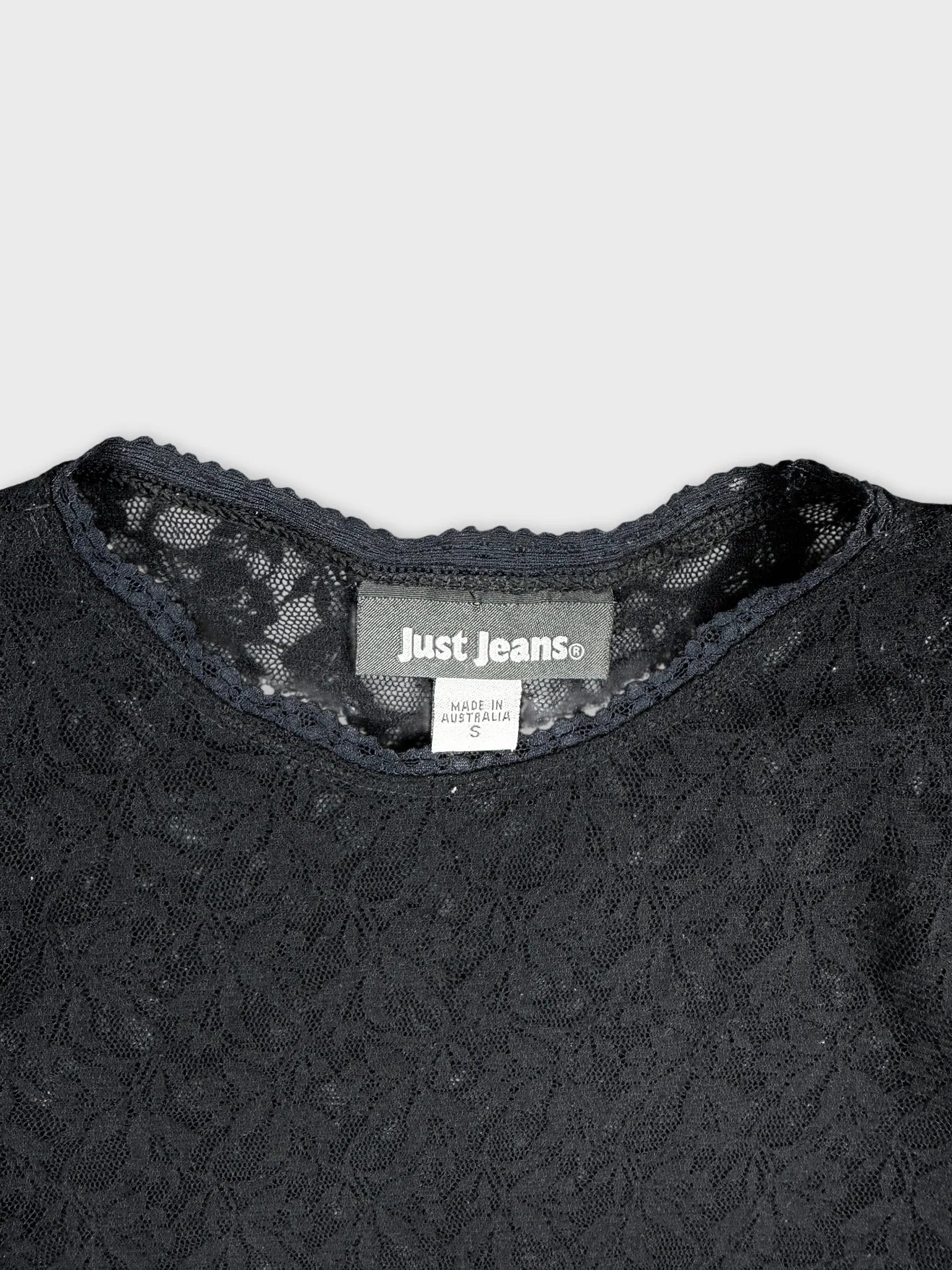 Detail view of a black lace body shirt with scalloped neckline.