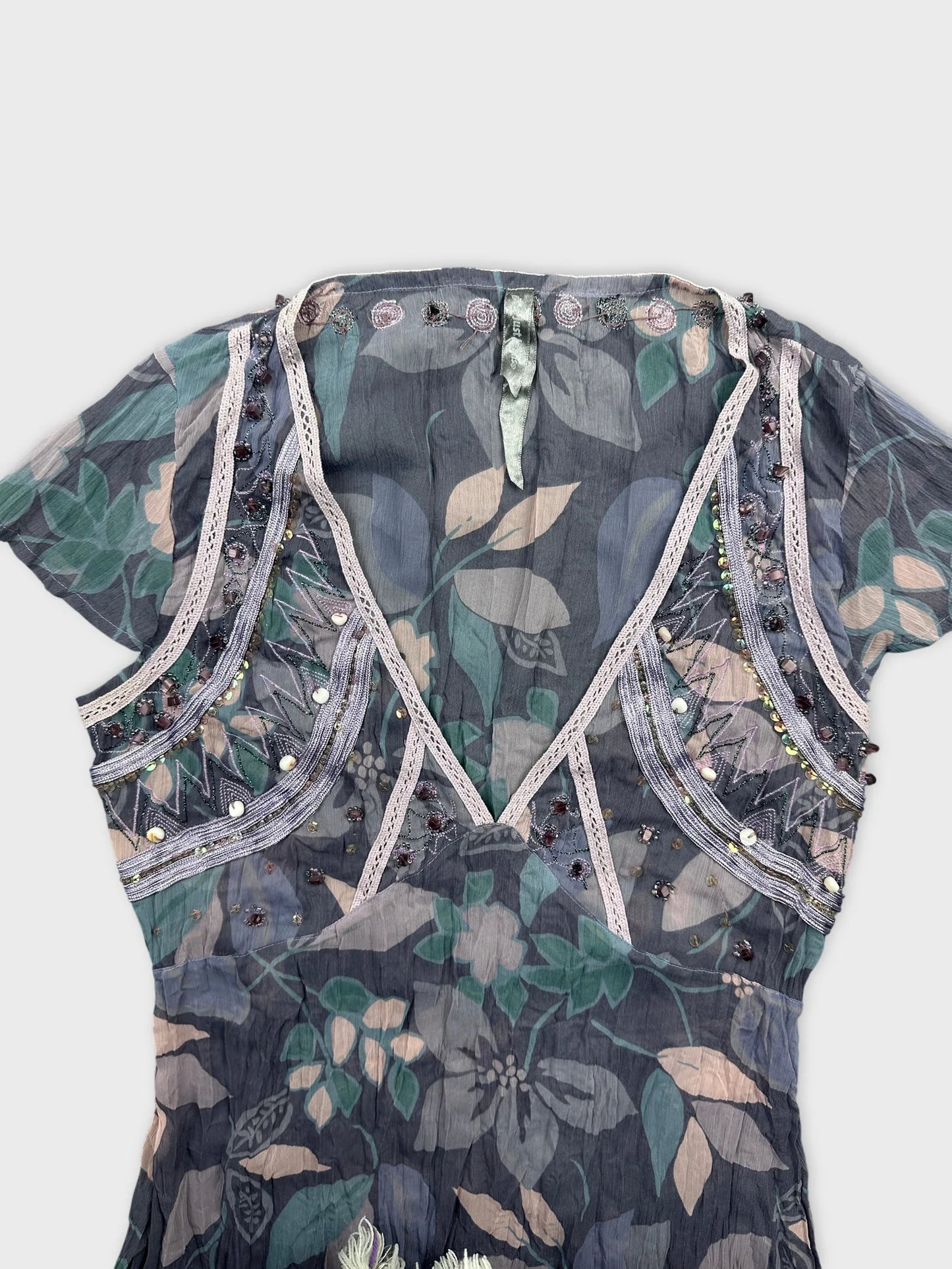 Detail view of a vintage body shirt in dark gray with floral pattern and decorative trim.