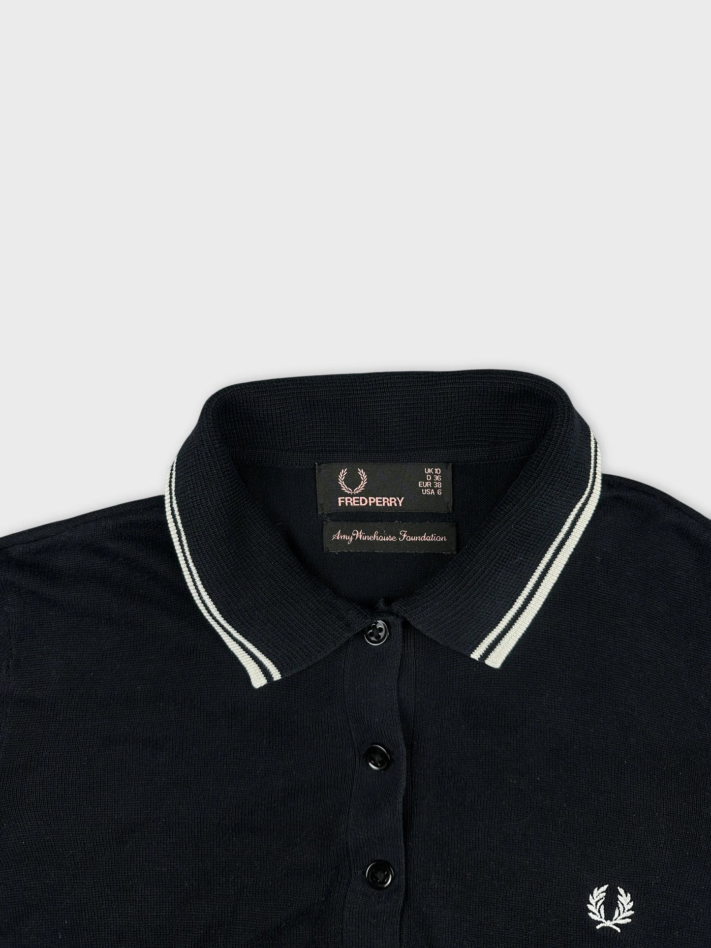 Detail view of a black polo shirt with striped collar and buttons.