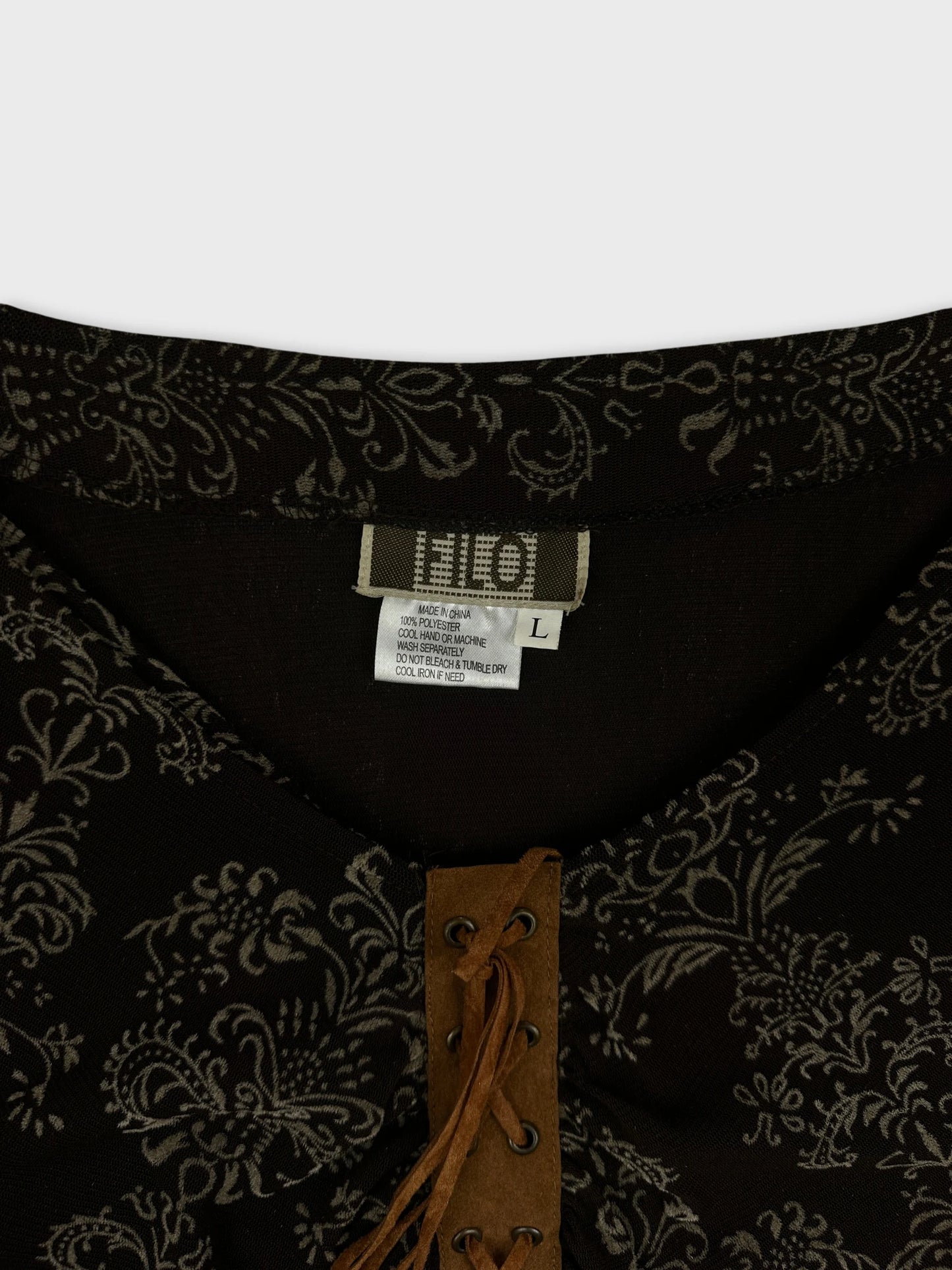 Detail view of a black body shirt featuring floral patterns and a lace-up front.