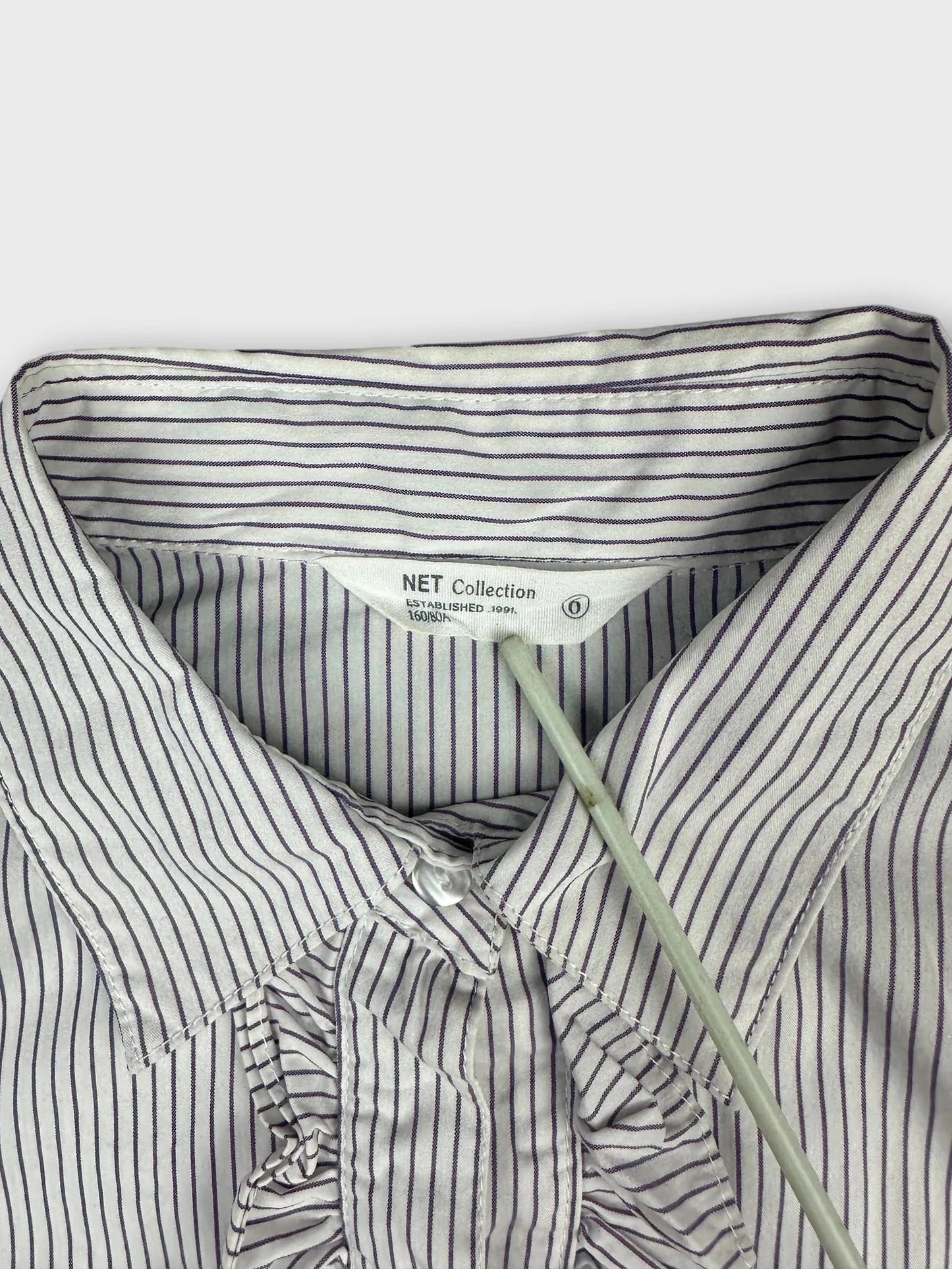 Detail view of a women’s body shirt in white with purple stripes.