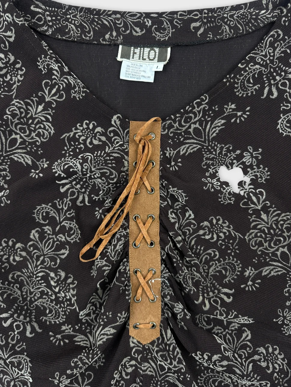 Detail view of a black vintage body shirt with floral print and lace-up front.