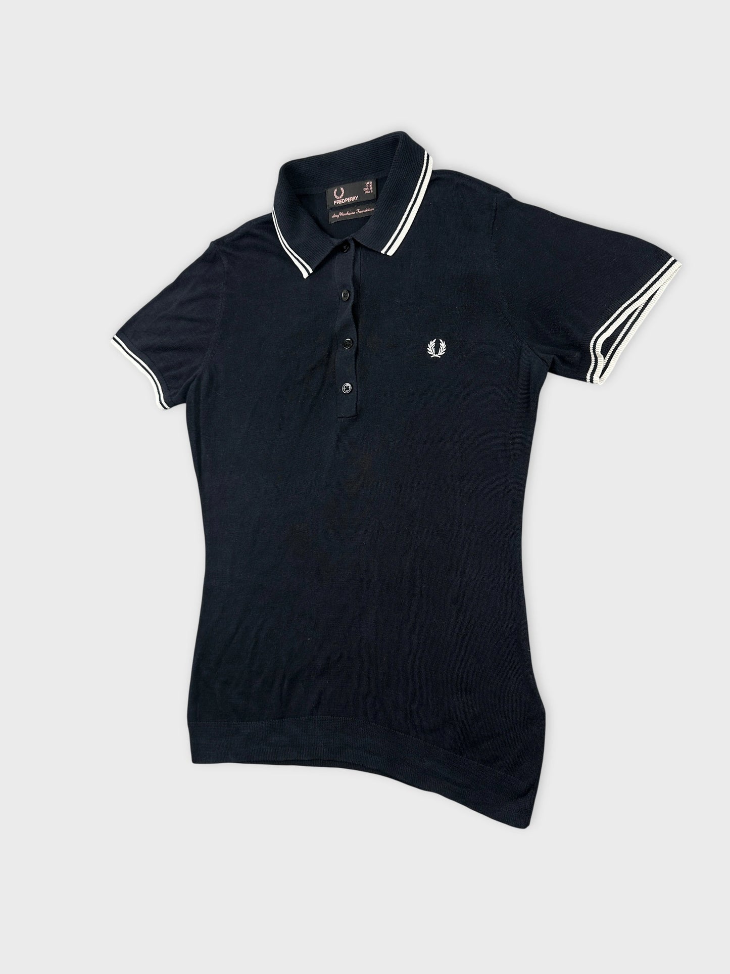 Detail view of a black polo shirt with white trim and logo