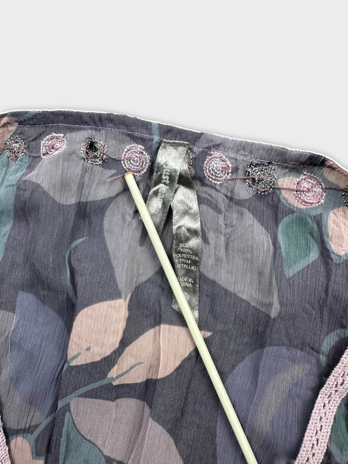 detail view of a sheer body shirt in gray with floral print and embroidered trim