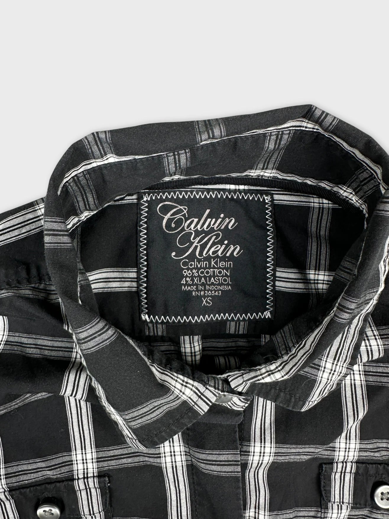 Detail view of a black and white plaid body t-shirt with collar.