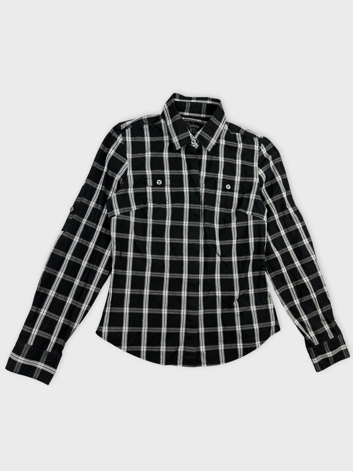 Detail view of a black and white plaid button-up shirt.