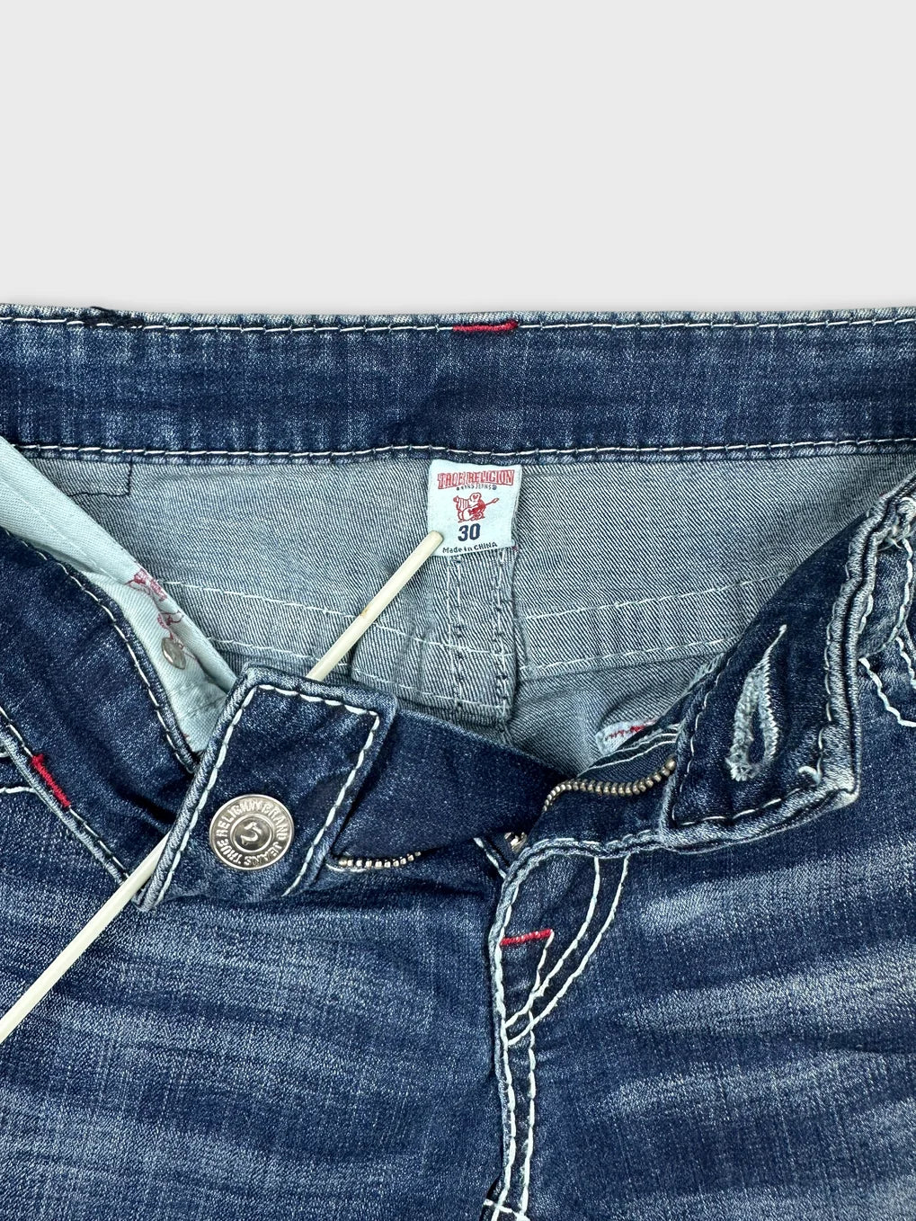 Detail view of denim mini shorts featuring dark blue fabric and contrasting red stitching