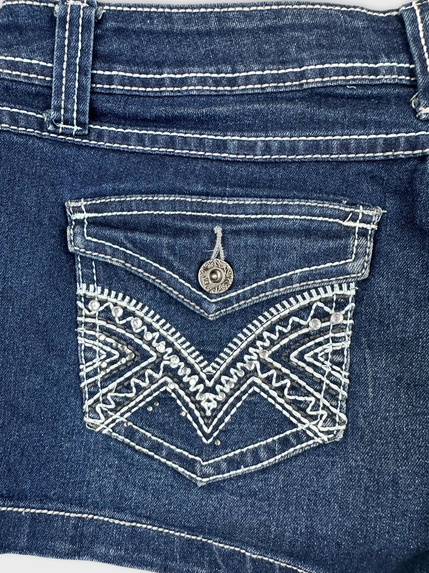 Detail view of blue denim shorts featuring decorative embroidered pocket design.